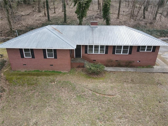 view of front of house featuring crawl space, brick siding, metal roof, and a chimney