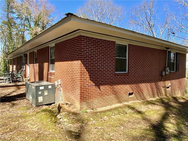 view of side of home with crawl space and brick siding