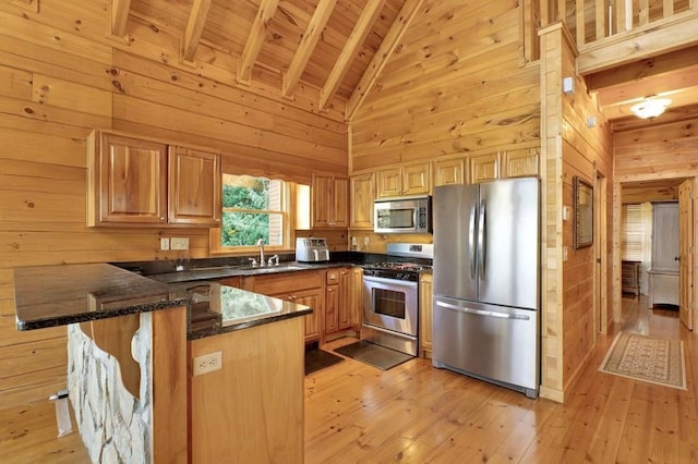 71 Hidden Valley Dr S, Ellijay, GA 30536 - kitchen featuring appliances with stainless steel finishes, wood walls, a peninsula, dark stone counters, and light wood-type flooring