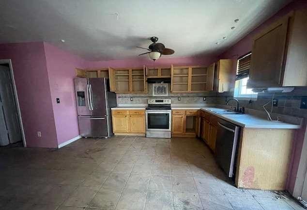 kitchen with a sink, light countertops, appliances with stainless steel finishes, open shelves, and tasteful backsplash