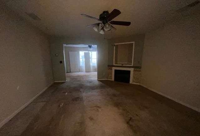 unfurnished living room with ceiling fan, a fireplace, and baseboards