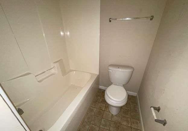 full bathroom featuring a bathtub, baseboards, toilet, and walk in shower