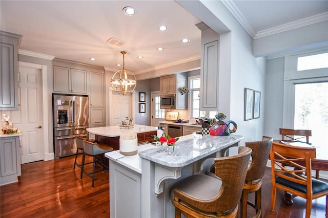 kitchen featuring appliances with stainless steel finishes, decorative light fixtures, a chandelier, crown molding, and a breakfast bar
