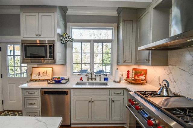 kitchen with a wealth of natural light, stainless steel appliances, wall chimney exhaust hood, and sink