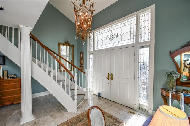 foyer entrance featuring a healthy amount of sunlight, decorative columns, and a high ceiling