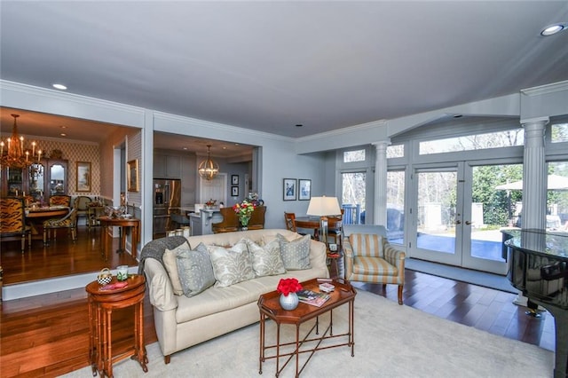 living room with decorative columns, ornamental molding, hardwood / wood-style flooring, and a chandelier