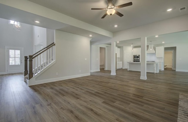 unfurnished living room featuring ceiling fan and dark wood-type flooring