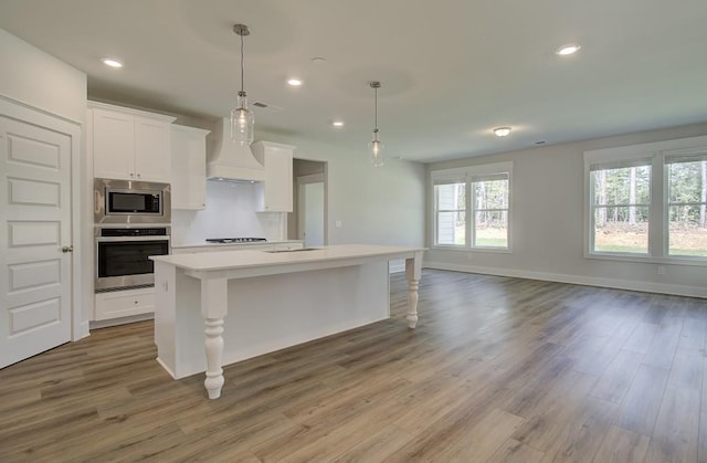 kitchen featuring a kitchen bar, appliances with stainless steel finishes, hardwood / wood-style flooring, and white cabinetry