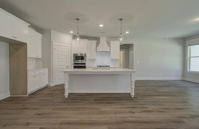 kitchen with decorative light fixtures, white cabinetry, custom range hood, and appliances with stainless steel finishes