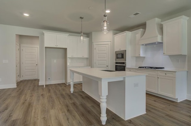 kitchen featuring hanging light fixtures, light hardwood / wood-style flooring, custom range hood, white cabinetry, and stainless steel appliances