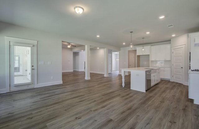 kitchen with a center island, stainless steel dishwasher, decorative light fixtures, white cabinets, and hardwood / wood-style flooring