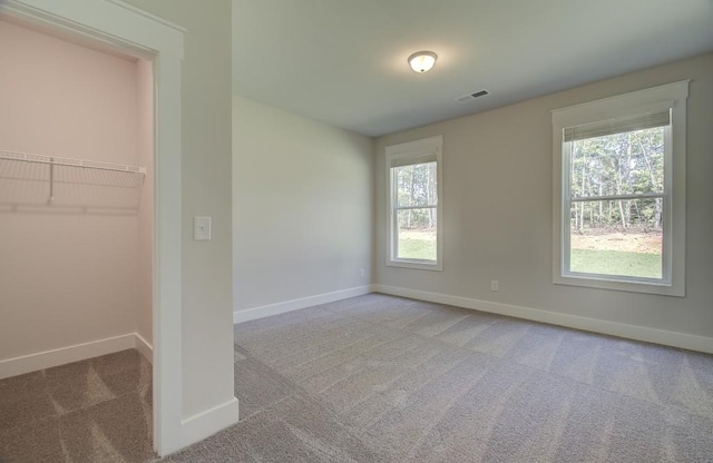 unfurnished bedroom with a walk in closet, light carpet, and a closet