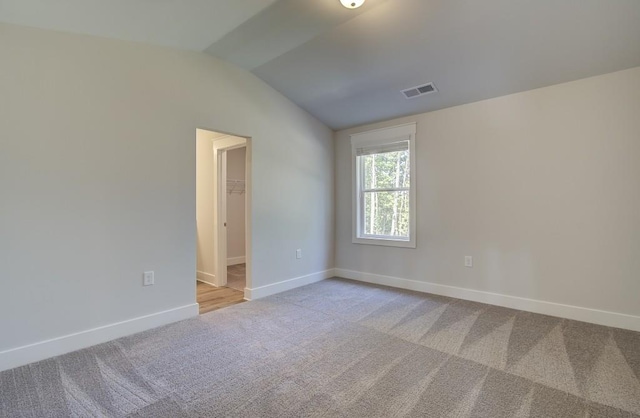 carpeted empty room featuring vaulted ceiling