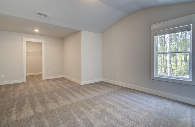 spare room featuring a wealth of natural light, light carpet, and lofted ceiling