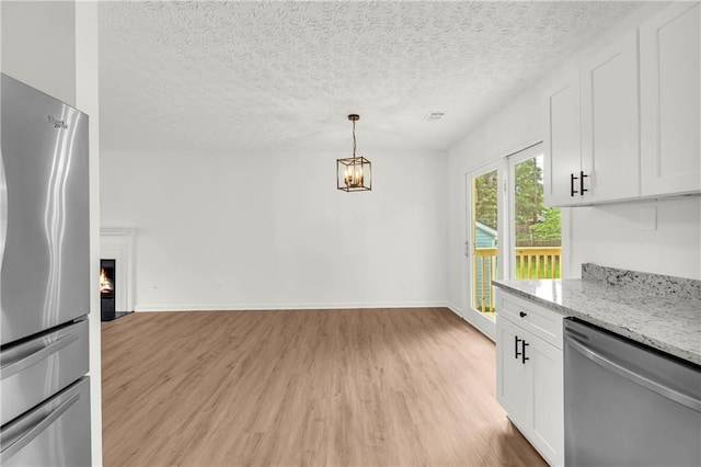 1645 Cobbs Creek Ln, Decatur, GA 30032 - kitchen featuring appliances with stainless steel finishes, light wood-type flooring, white cabinetry, light stone countertops, and a textured ceiling