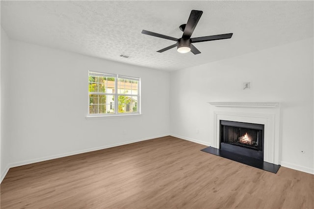 1645 Cobbs Creek Ln, Decatur, GA 30032 - unfurnished living room with wood finished floors, a warm lit fireplace, ceiling fan, baseboards, and a textured ceiling