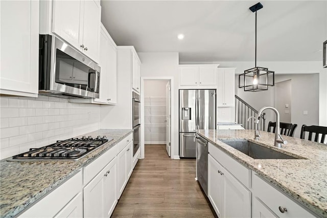 kitchen featuring a sink, white cabinets, appliances with stainless steel finishes, backsplash, and dark wood-style floors