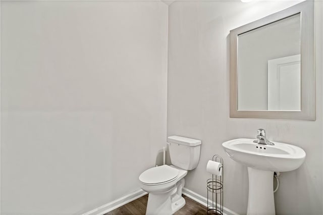 bathroom with baseboards, toilet, and wood finished floors