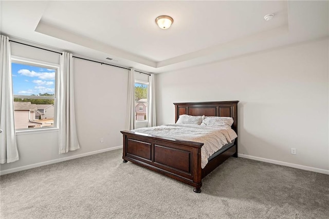 bedroom with baseboards, a tray ceiling, and light colored carpet