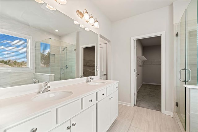 full bath with a spacious closet, double vanity, a stall shower, and a sink