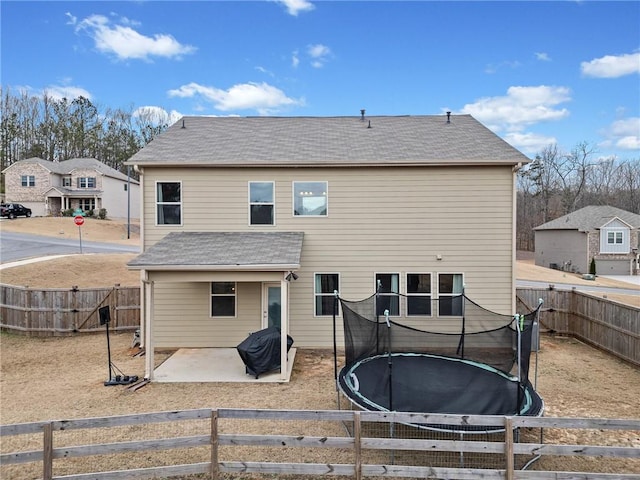 rear view of house with a fenced backyard, a trampoline, and a patio