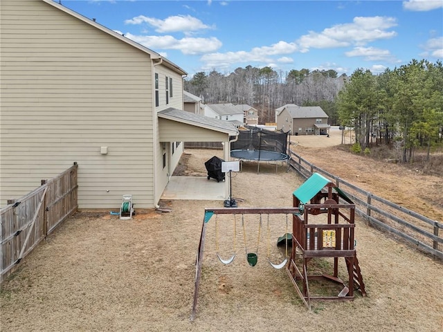 view of yard featuring a trampoline, fence, a playground, and a patio