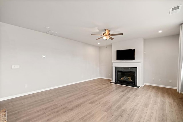 unfurnished living room with light wood finished floors, a fireplace, a ceiling fan, and baseboards