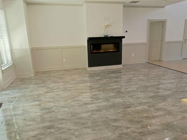 4590 River Stone Trl, Douglasville, GA 30135 - unfurnished living room featuring a glass covered fireplace, a wainscoted wall, and a decorative wall