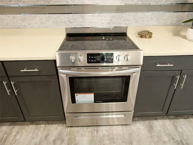 4590 River Stone Trl, Douglasville, GA 30135 - kitchen with stainless steel range with electric cooktop, backsplash, light countertops, and gray cabinets