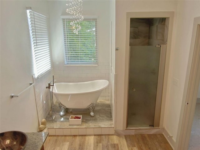4590 River Stone Trl, Douglasville, GA 30135 - full bathroom with tile walls, wood finished floors, a freestanding bath, a shower stall, and a chandelier
