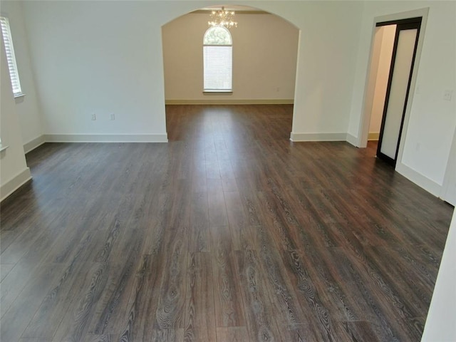 4590 River Stone Trl, Douglasville, GA 30135 - unfurnished living room featuring arched walkways, dark wood finished floors, baseboards, and a chandelier