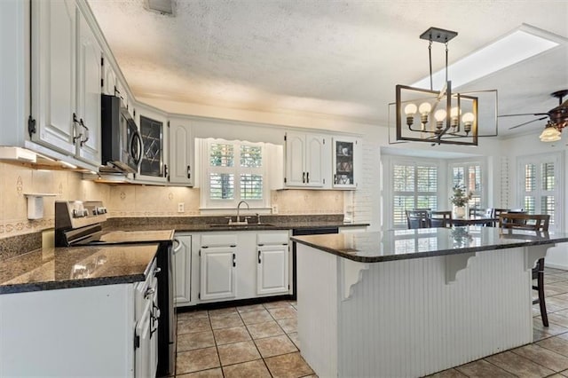 263 Mountainview Cir, Canton, GA 30115 - kitchen with electric range, a kitchen breakfast bar, backsplash, light tile patterned flooring, and a textured ceiling