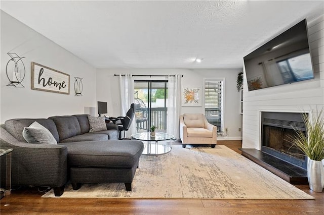 living room with a large fireplace, a textured ceiling, and wood finished floors