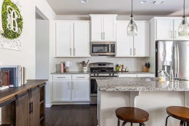 2099 Lakeview Bend Way, Buford, GA 30519 - kitchen with stainless steel appliances, dark wood-type flooring, a breakfast bar area, tasteful backsplash, and recessed lighting