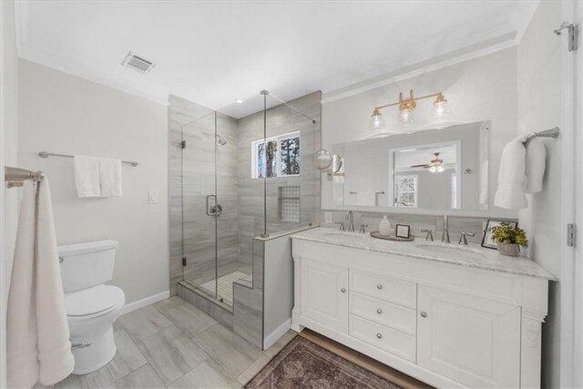 bathroom featuring double vanity, toilet, a stall shower, and a sink