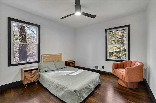 bedroom with multiple windows, dark wood-type flooring, and ceiling fan