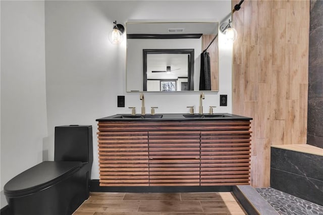 bathroom with tiled shower, vanity, and toilet