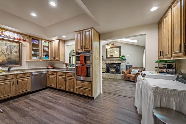 kitchen with a sink, separate washer and dryer, dark wood-type flooring, a fireplace, and appliances with stainless steel finishes