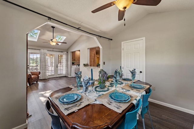 dining area featuring a ceiling fan, lofted ceiling with skylight, french doors, and wood finished floors