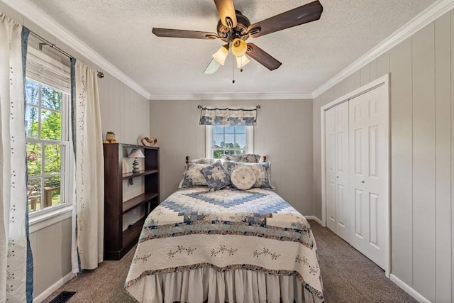 bedroom featuring a closet, a textured ceiling, ornamental molding, carpet flooring, and ceiling fan