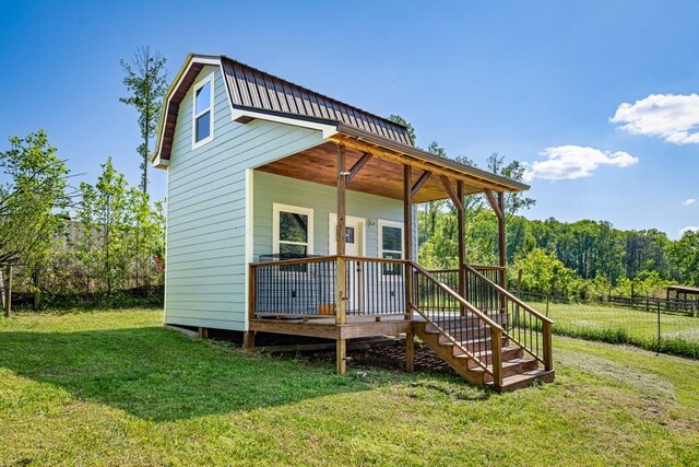 rear view of house featuring a lawn, stairway, and fence