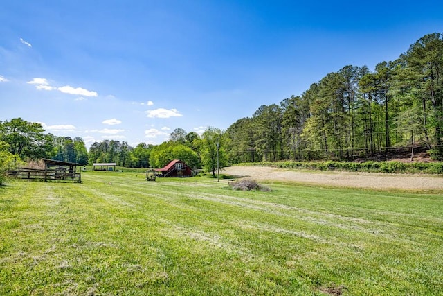 view of yard with a rural view, a forest view, and fence