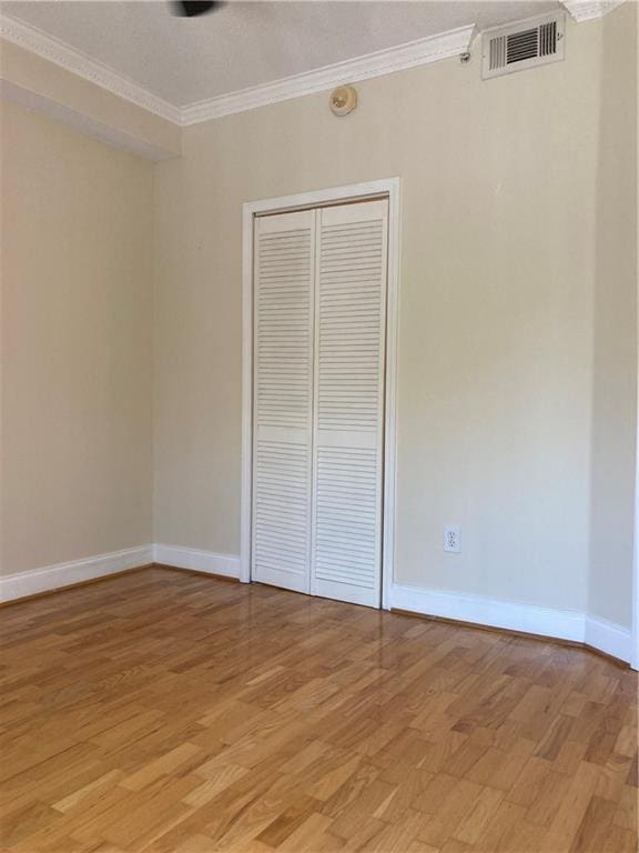 1075 Peachtree Walk Unit A205, Atlanta, GA 30309 - unfurnished bedroom featuring ornamental molding, light wood-style floors, and a closet