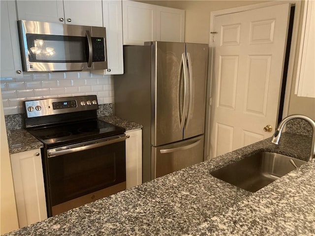 1075 Peachtree Walk Unit A205, Atlanta, GA 30309 - kitchen with stainless steel appliances, white cabinetry, dark stone countertops, and backsplash