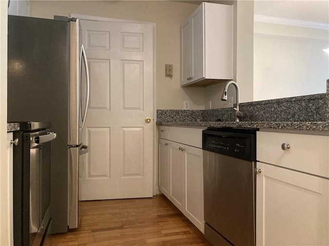 1075 Peachtree Walk Unit A205, Atlanta, GA 30309 - kitchen with stainless steel appliances, light wood-style flooring, white cabinets, crown molding, and dark stone countertops