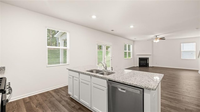 kitchen featuring stainless steel appliances, a sink, a glass covered fireplace, dark wood-style flooring, and white cabinetry