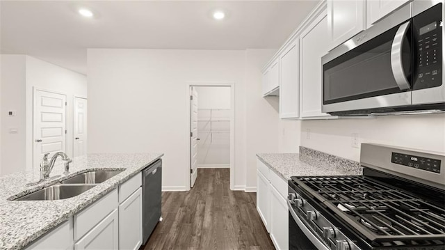 kitchen with stainless steel appliances, a sink, dark wood finished floors, white cabinets, and baseboards