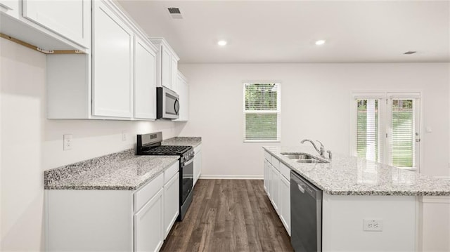 kitchen featuring appliances with stainless steel finishes, a sink, white cabinetry, dark wood-style floors, and a center island with sink