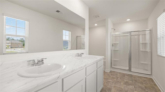 bathroom featuring a stall shower, double vanity, baseboards, recessed lighting, and stone finish flooring