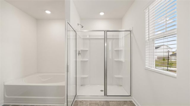 full bath with a stall shower, a garden tub, and baseboards